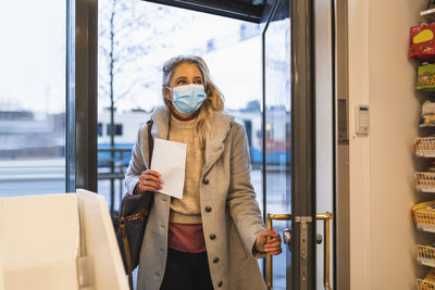 Mid adult female customer entering retail store during covid-19