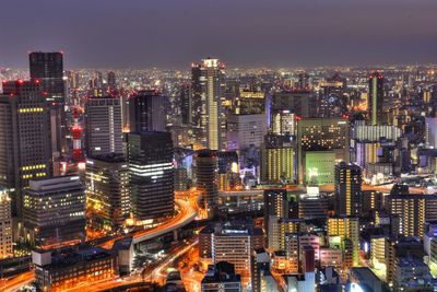 High angle view of illuminated city buildings against sky at night