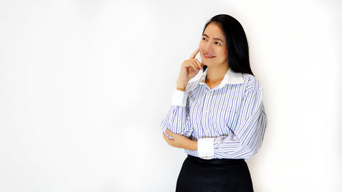 Businesswoman contemplating while standing against white background