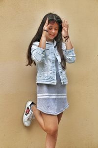 Portrait of smiling young woman standing against wall