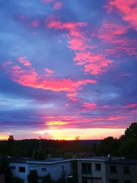 Silhouette houses and trees against sky at sunset