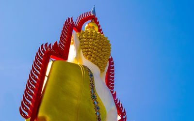 Low angle view of buddha statue against clear sky on sunny day