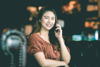 Portrait of smiling young woman using smart phone outdoors