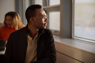 Man in glasses looking through window