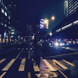 Man on illuminated city street against sky at night