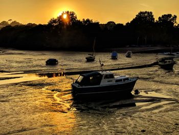 Boat moored on shore against sky during sunset