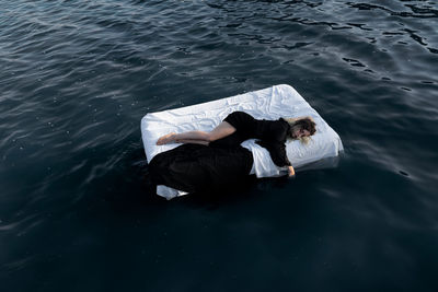 High angle view of young woman sleeping on bed floating in lake