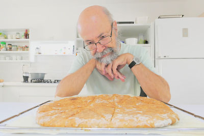 Senior man looking home made bread on table