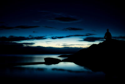 Silhouette man standing by sea against sky during sunset