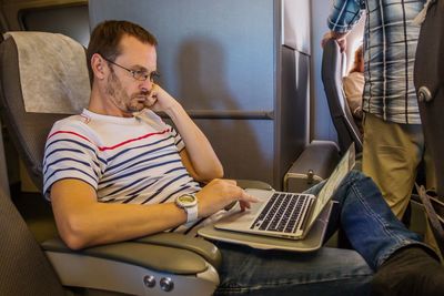 Man using laptop while traveling in airplane