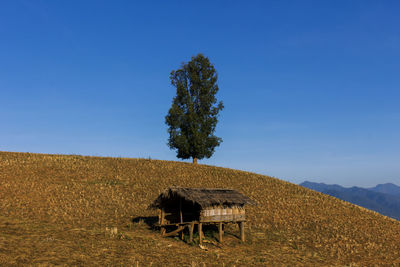 Built structure on field against clear blue sky