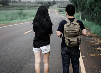 Rear view of people walking on road in city