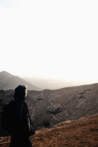 Rear view of man standing on mountain against sky