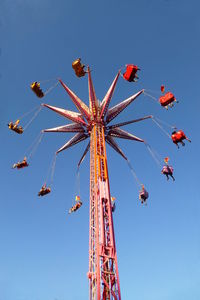 Low angle view of chain swing ride against clear blue sky