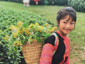 Portrait of woman standing by flowering plants