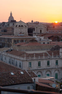 Buildings in city against sky during sunset