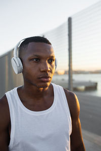 Serious african american runner listening to songs in headphones during break in active training in evening