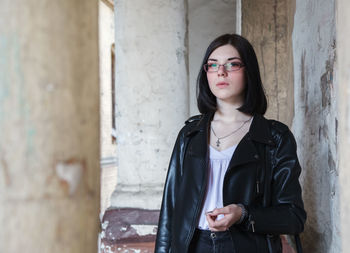 Portrait of young woman standing against wall