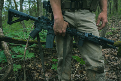 Low section of man holding camera in forest