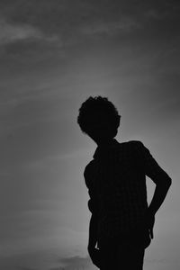 Low angle view of silhouette boy standing against sky