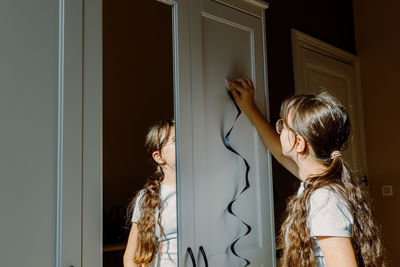 The girl hangs halloween decor on the closet.