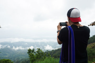 Rear view of woman photographing against sky