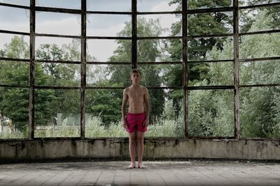 Full length of shirtless boy standing in abandoned building