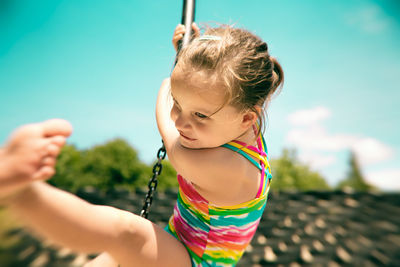 Woman holding girl against sky