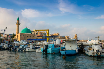 Boats moored in canal by buildings against sky