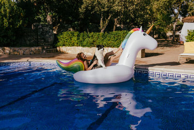 People relaxing in swimming pool against trees