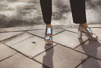 Woman wearing silver sandals, low section