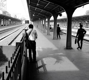 Rear view of people walking on railroad station platform