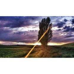 Scenic view of grassy field against cloudy sky