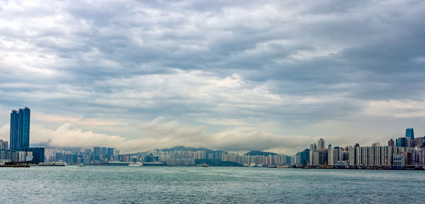 City at waterfront against cloudy sky