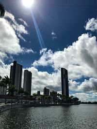 Modern cityscape by sea against sky