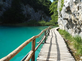 Wooden walkway by sea against mountain