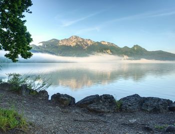 Pebble or rocky shore of the mountain lake, in the distance you can see the sharp alps mountains