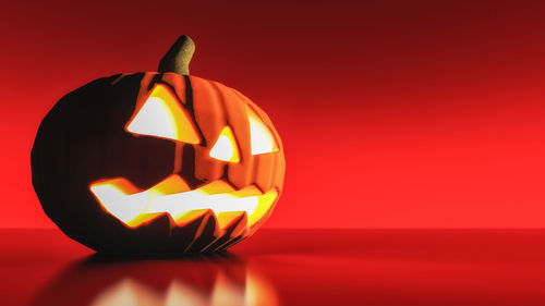 Close-up of illuminated pumpkin against red background