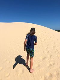 Full length rear view of man standing on desert