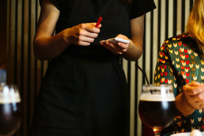 Waitress taking and order from blonde woman on green blouse in restaurant, cafe, pizzeria. 