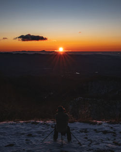 Rear view of people standing on snow covered land during sunrise