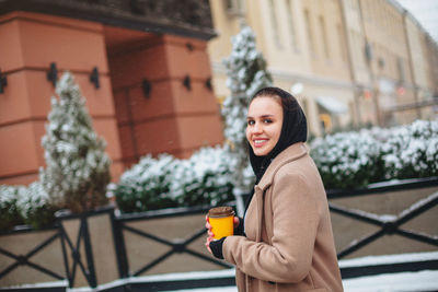 Portrait of smiling woman standing against plants in winter