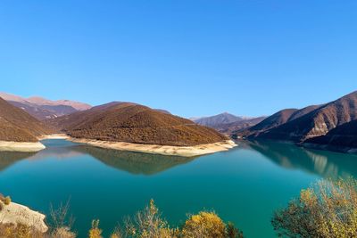 Panoramic view of lake and mountains against clear blue sky