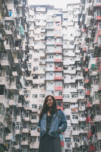 Portrait of woman standing against buildings in city