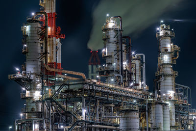 Illuminated factory against sky at night