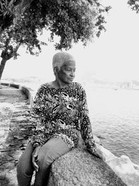 Full length of woman sitting by lake