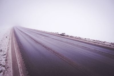 Tire tracks on road against clear sky