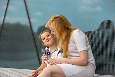 Happy blond woman and little boy sitting on terrace and eating sweets. mother and son