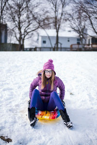 Pre teen sitting on sled in the snow in winter