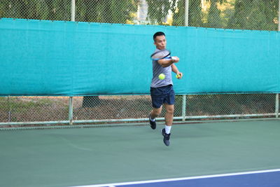 Full length of man playing tennis in court